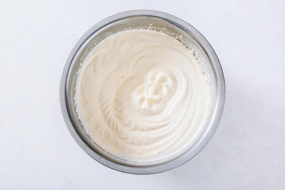 Mousse for mandarin orange cake in a silver bowl.