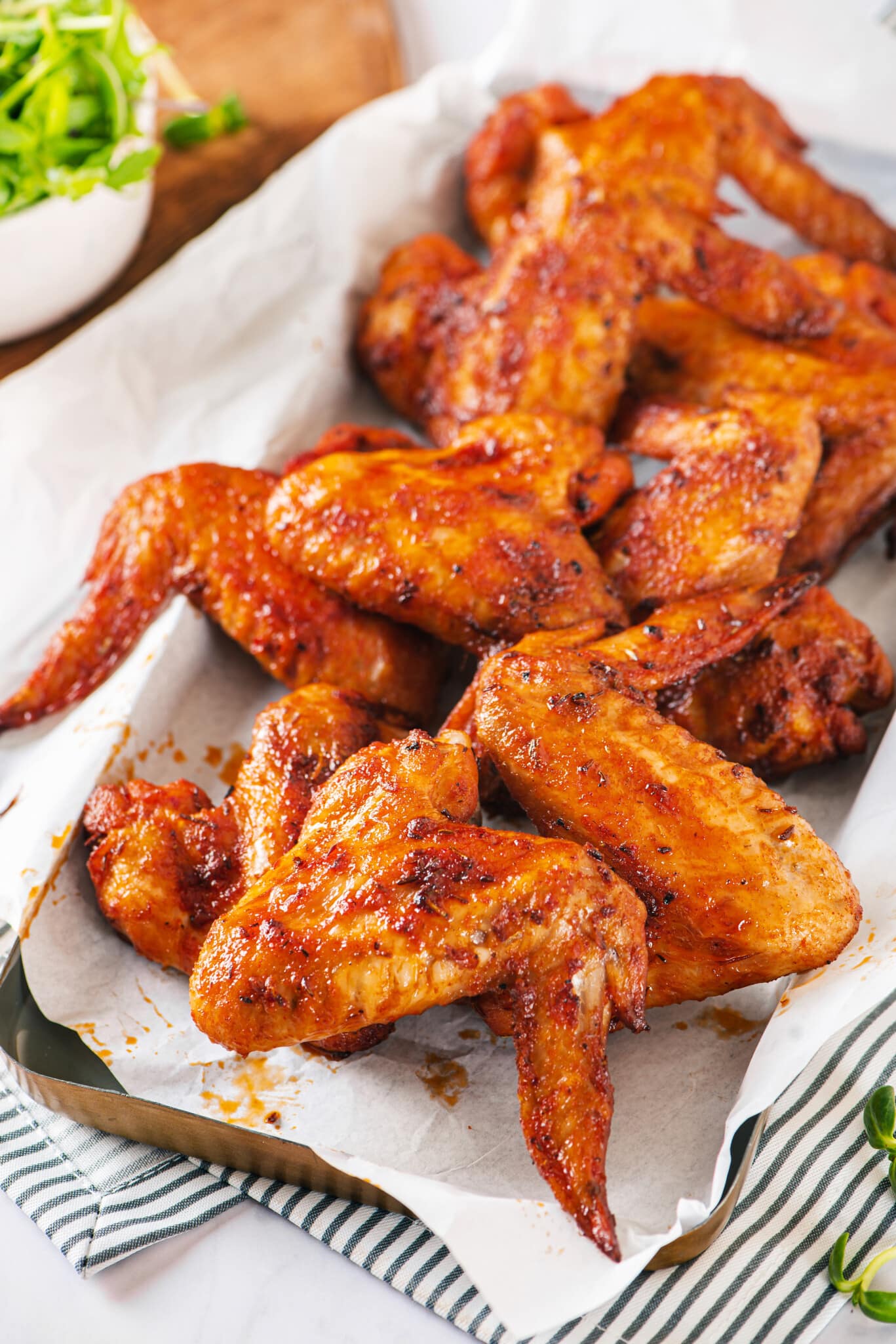 chicken-wings-on-parchment-paper-tray-on-a-striped-towel-with-arugula-on-the-side