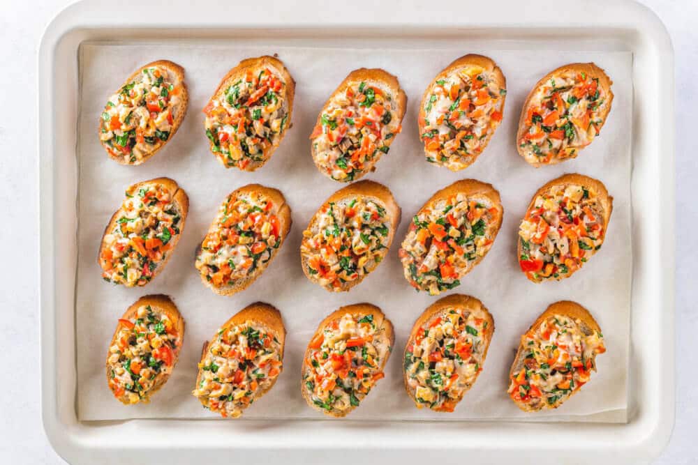 Bruschetta on a baking sheet lined with parchment paper.