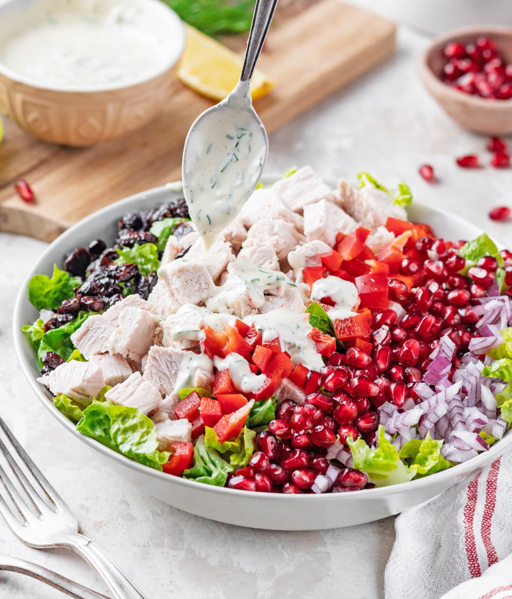 turkey-salad-recipe-on-a-white-plate-with-a-silver-fork-and-a-spoon-drizzling-dressing