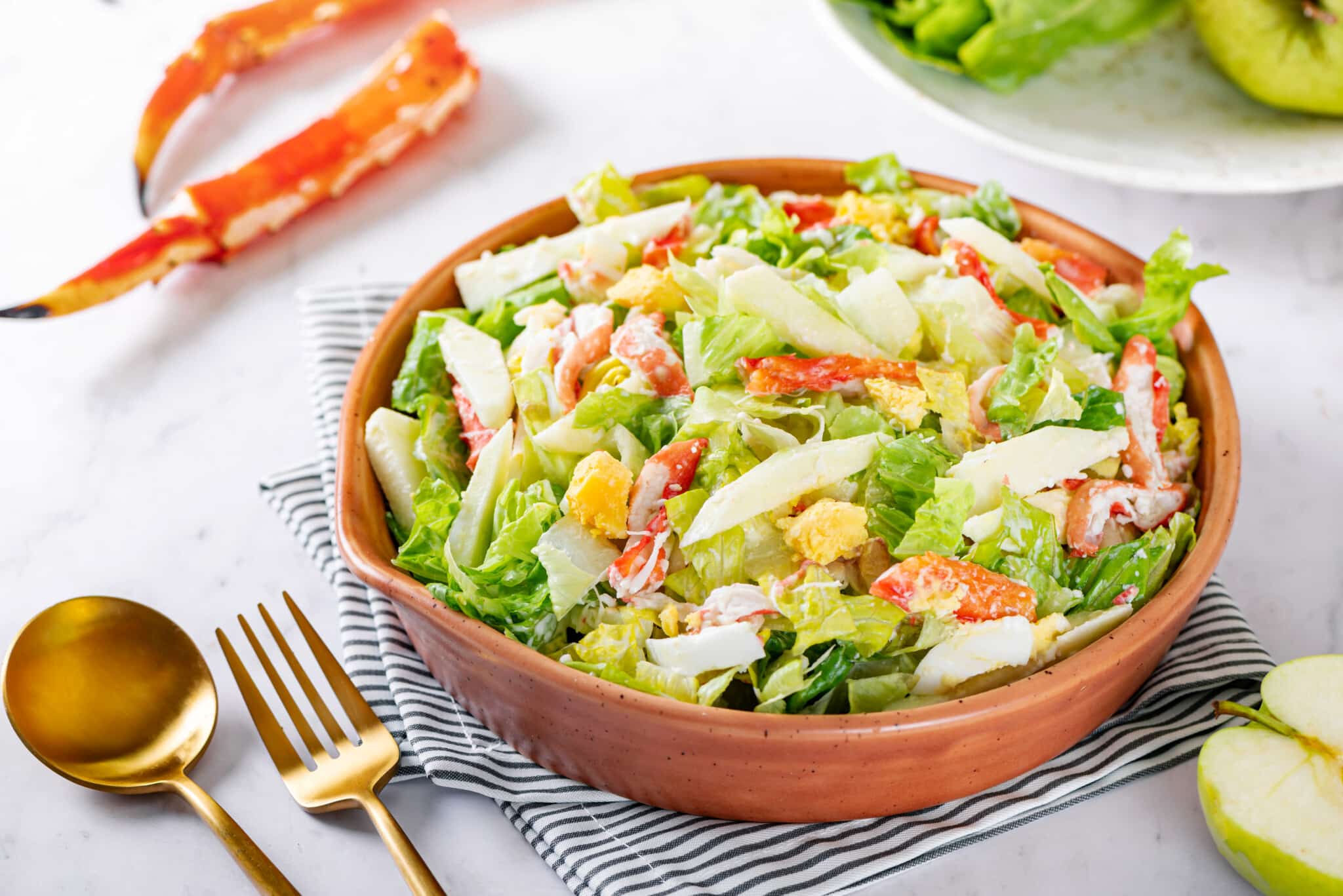 Crab and apple salad with a gold fork and spoon on the side.