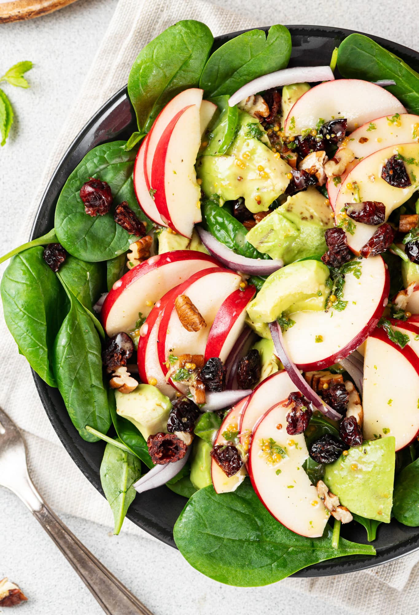 A bowl of apple, spinach, avocado salad.