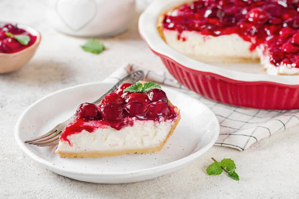 Cheesecake slice on a white plate with a fork.