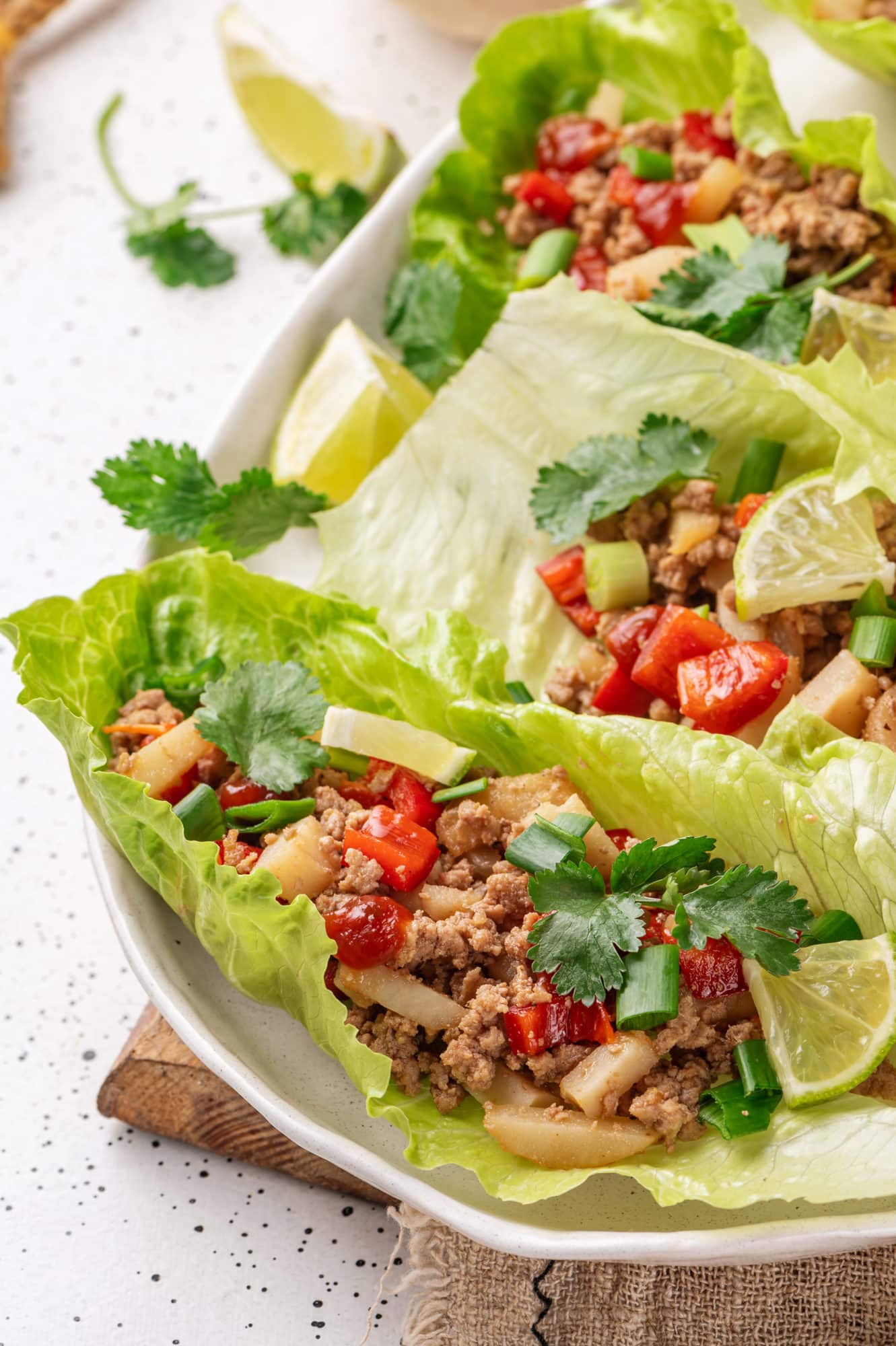 Close up of turkey filling in lettuce wraps on a white plate.