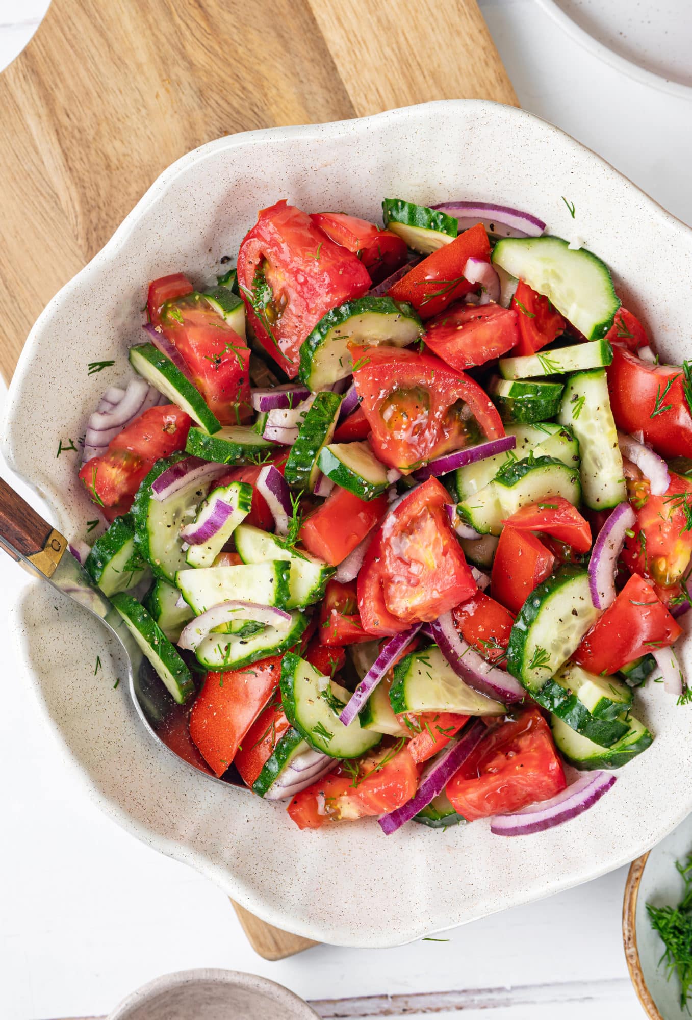 Summer salad in a white bowl with a spoon.