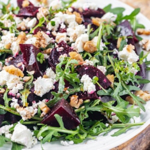 a white plate on a wooden board with beet salad.