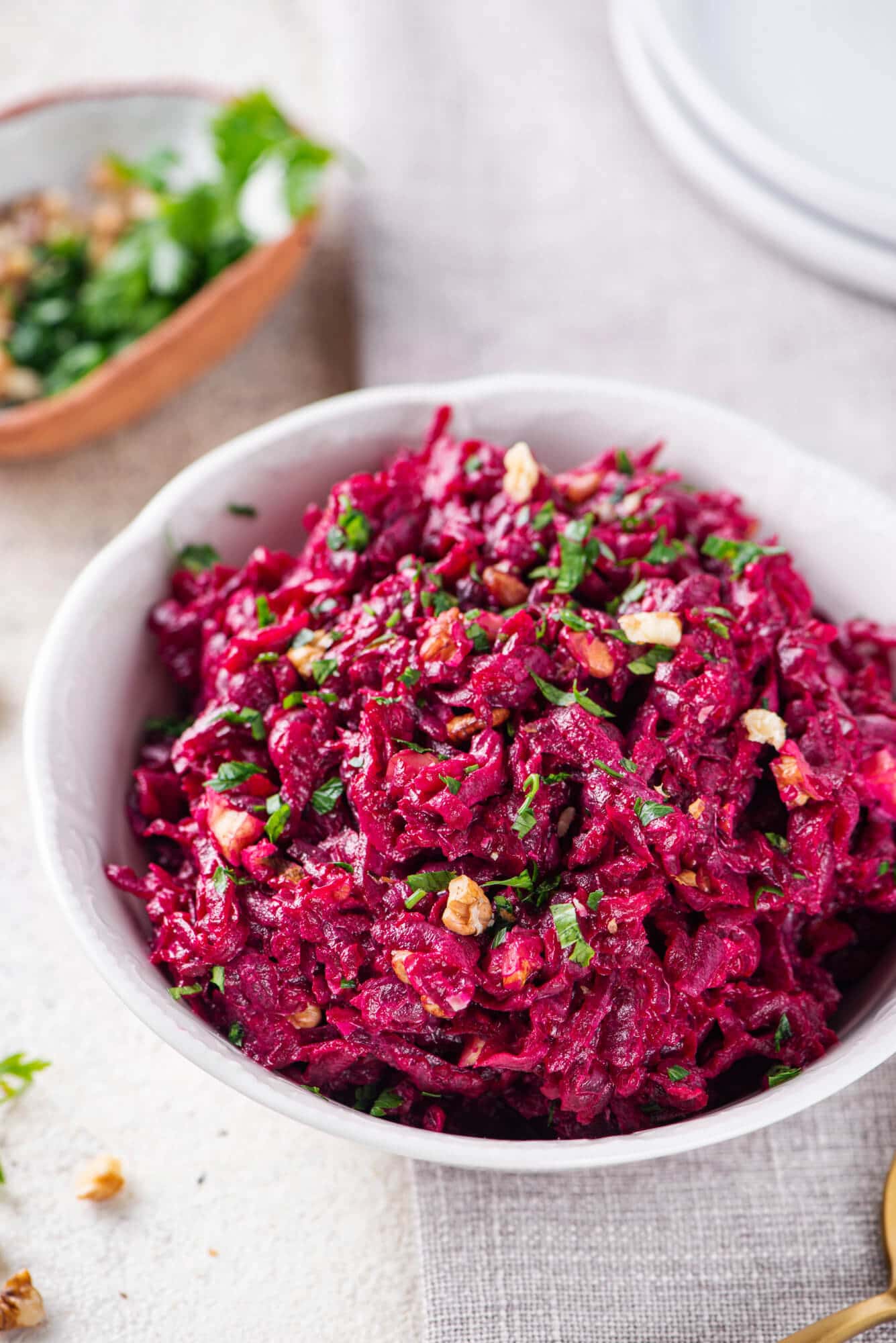 Beet salad in a white bowl with parsley sprinkled on top.