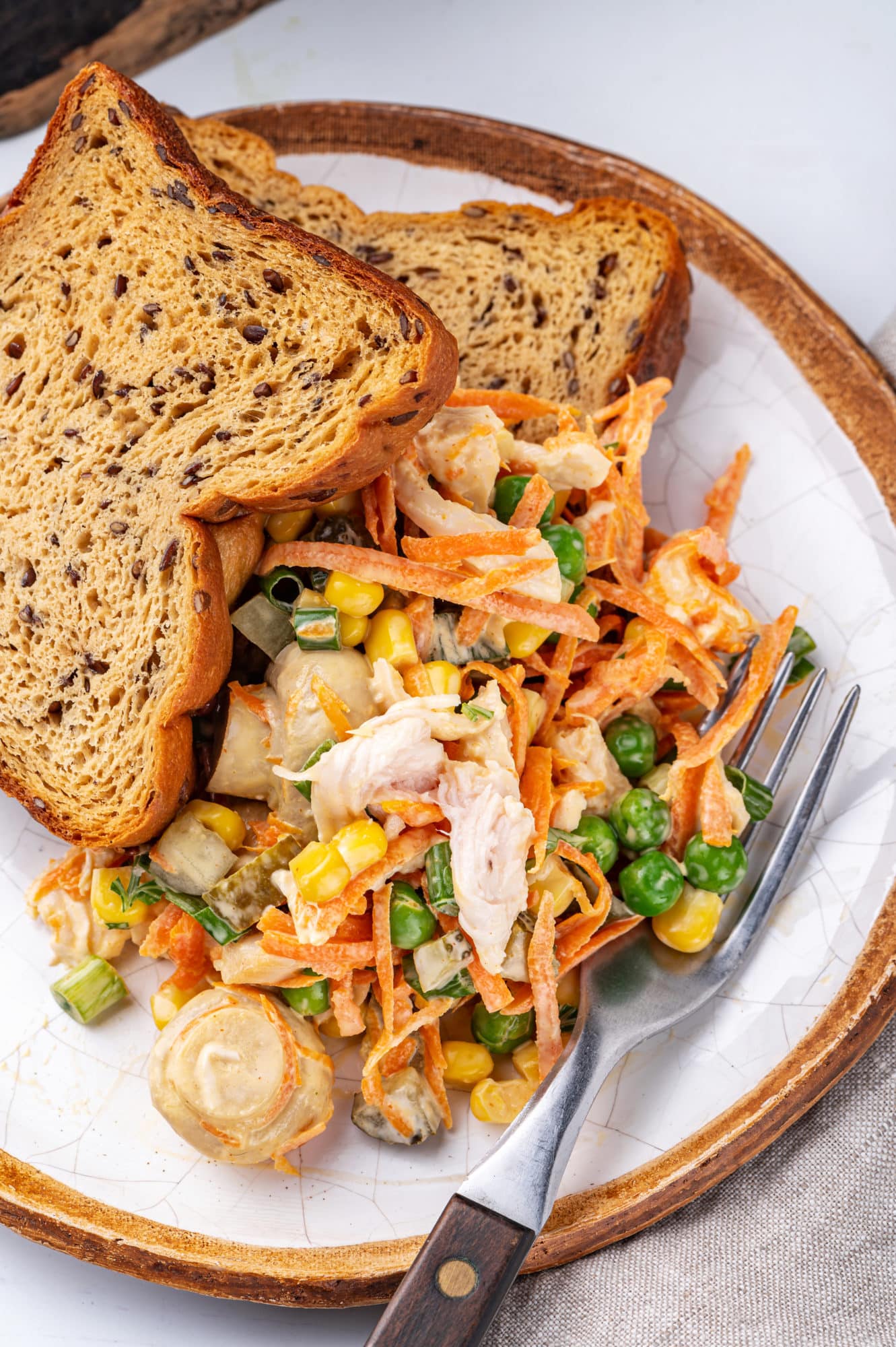 chicken mushroom veggie salad on a white plate with a fork bread slices on the side of the plate.