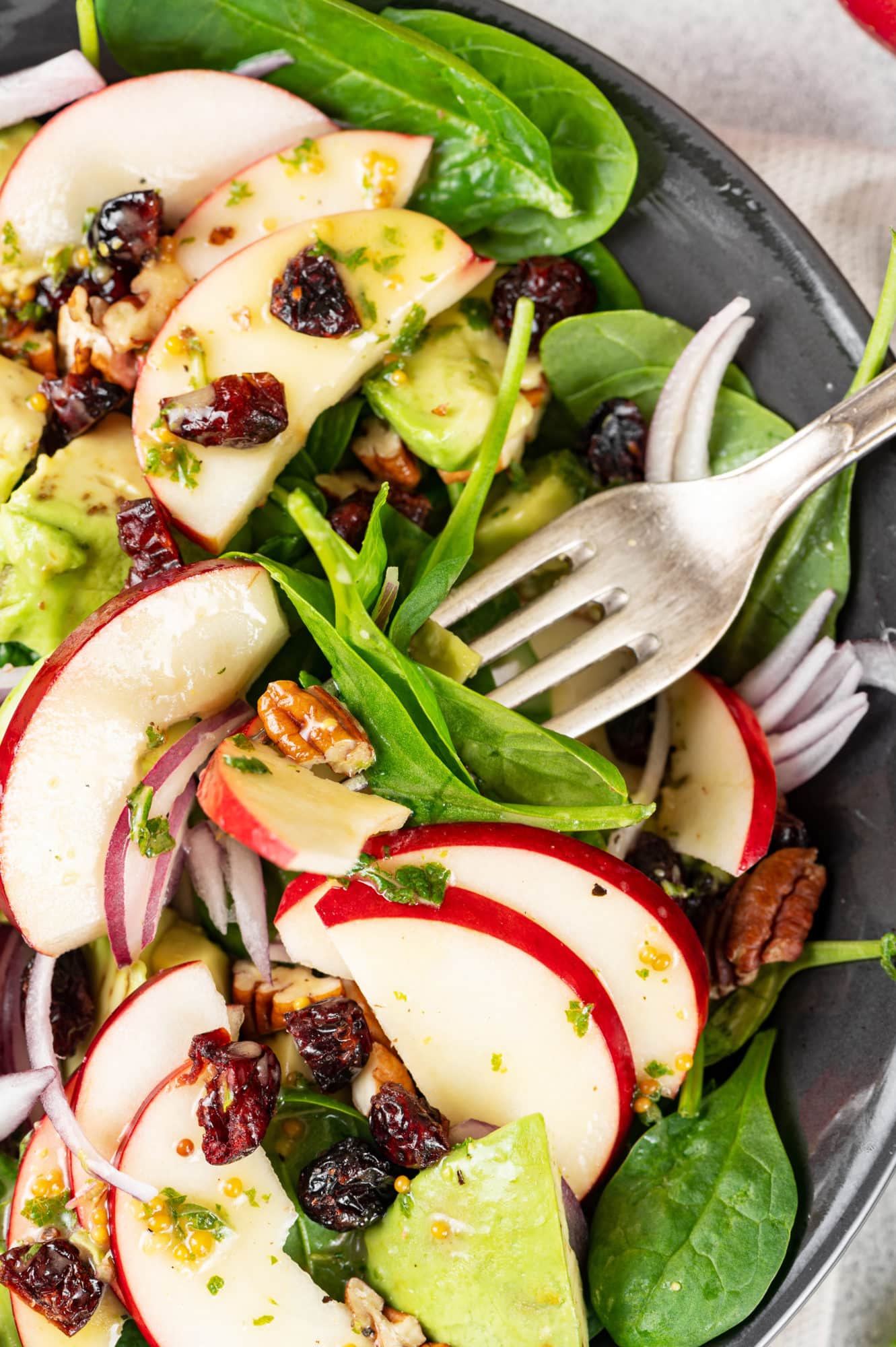 A bowl of apple, spinach, avocado salad.