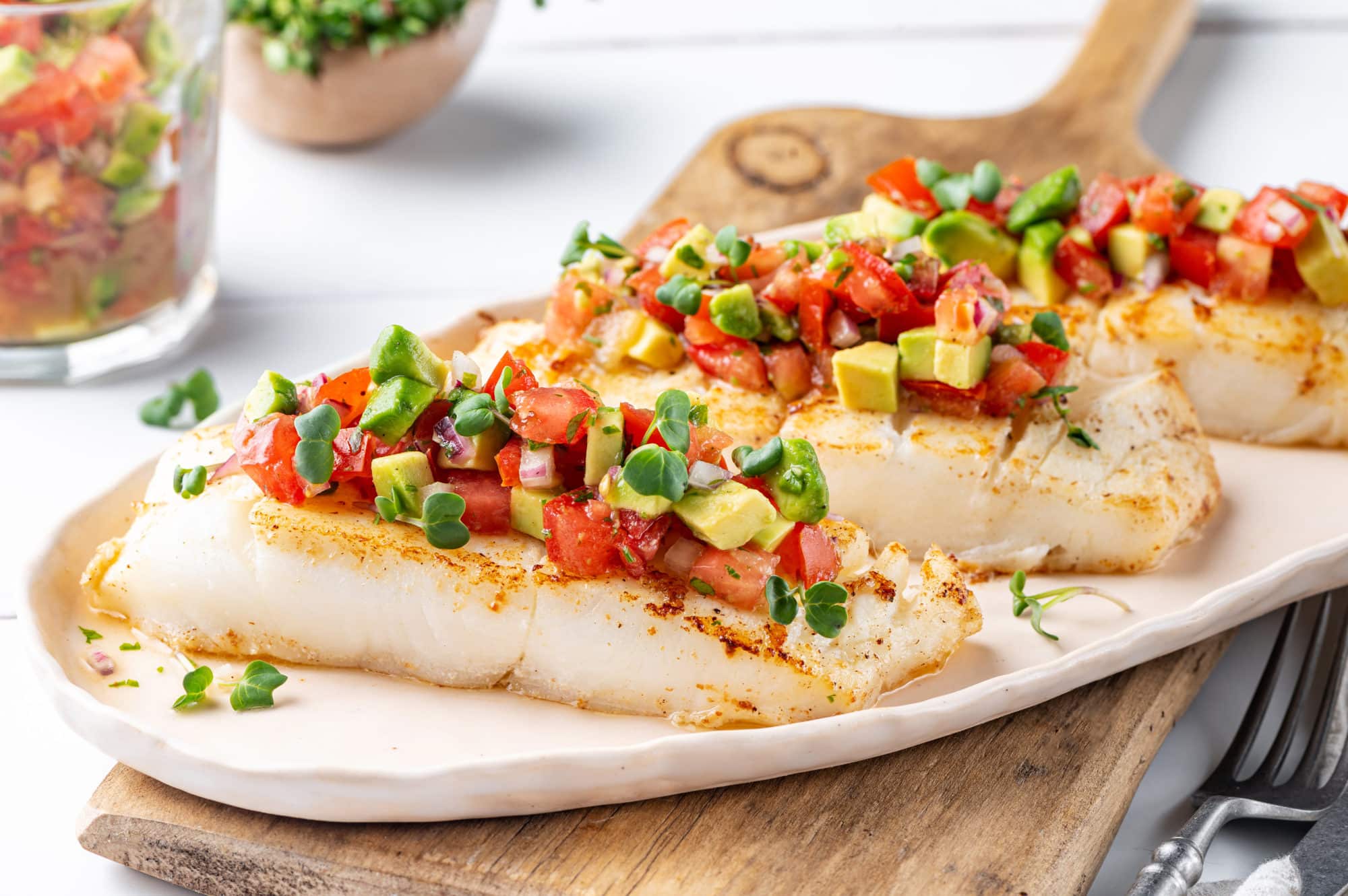 halibut-with-salsa-on-a-white-plate-on-a-wooden-board-with-a-fork-on-the-side