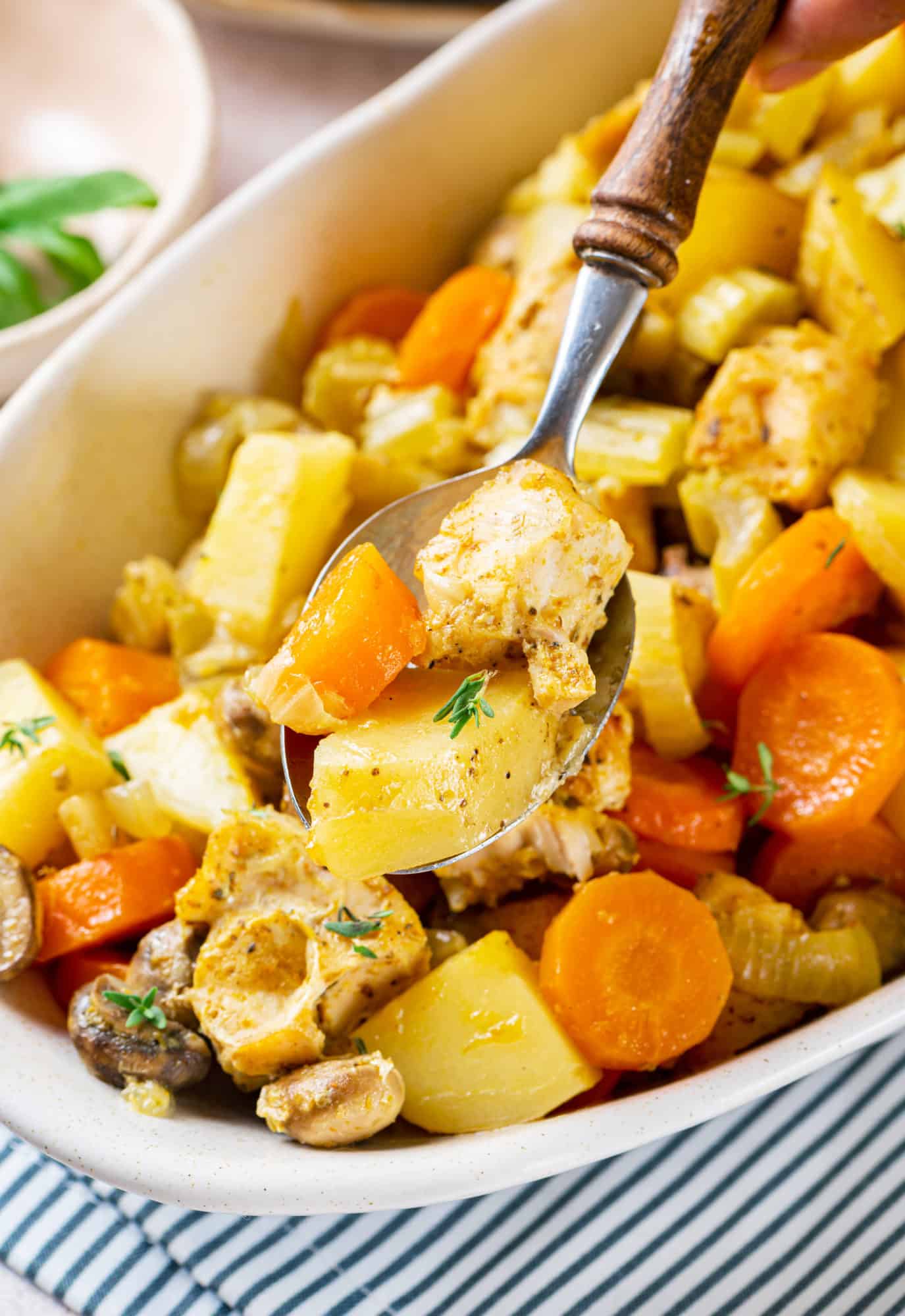 vegetables-with-chicken-in-a-white-bowl-with-a-spoon-on-a-striped-towel