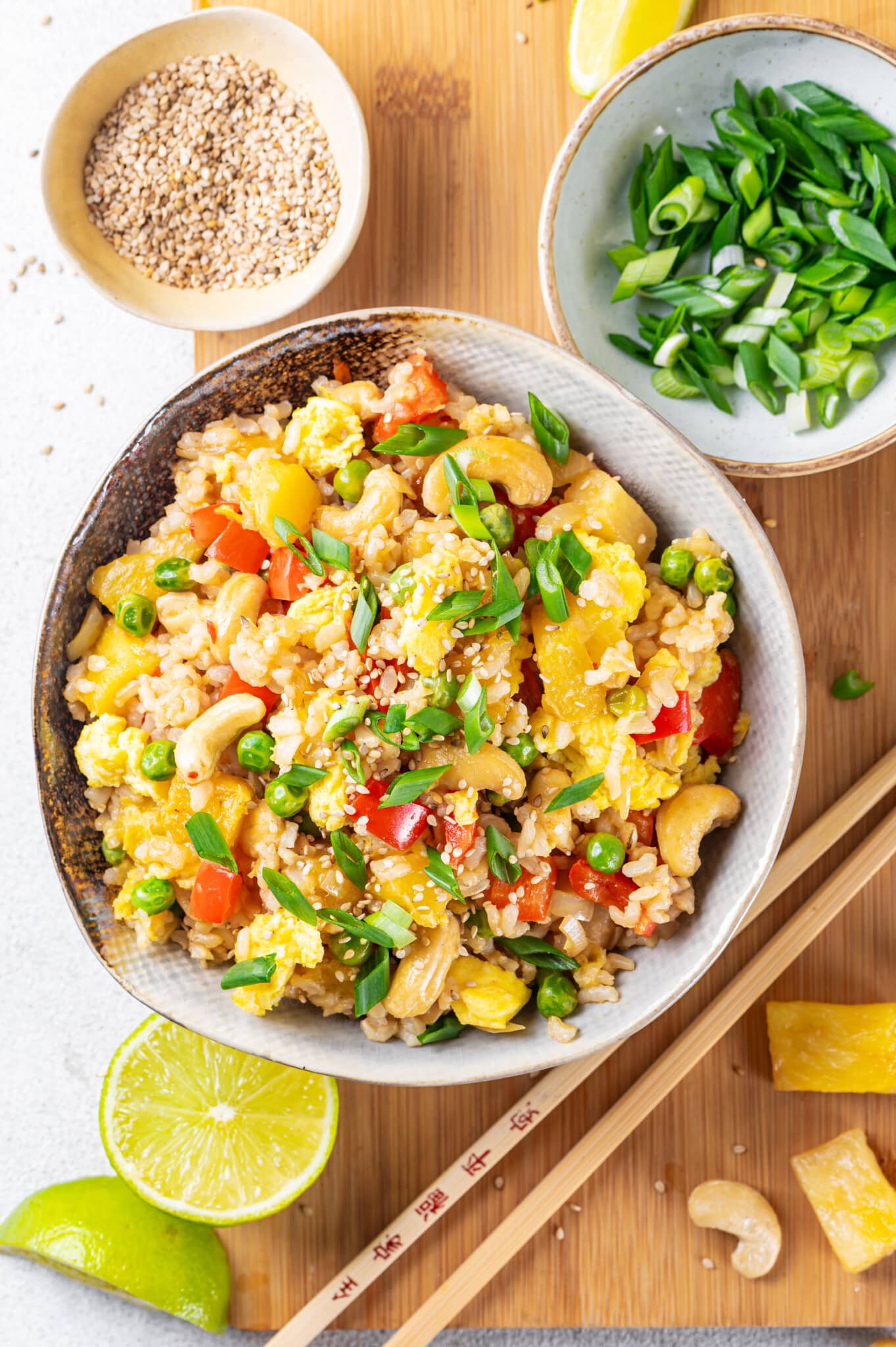 pineapple fried rice in a grey bowl with scallions on top and chopsticks on the side.