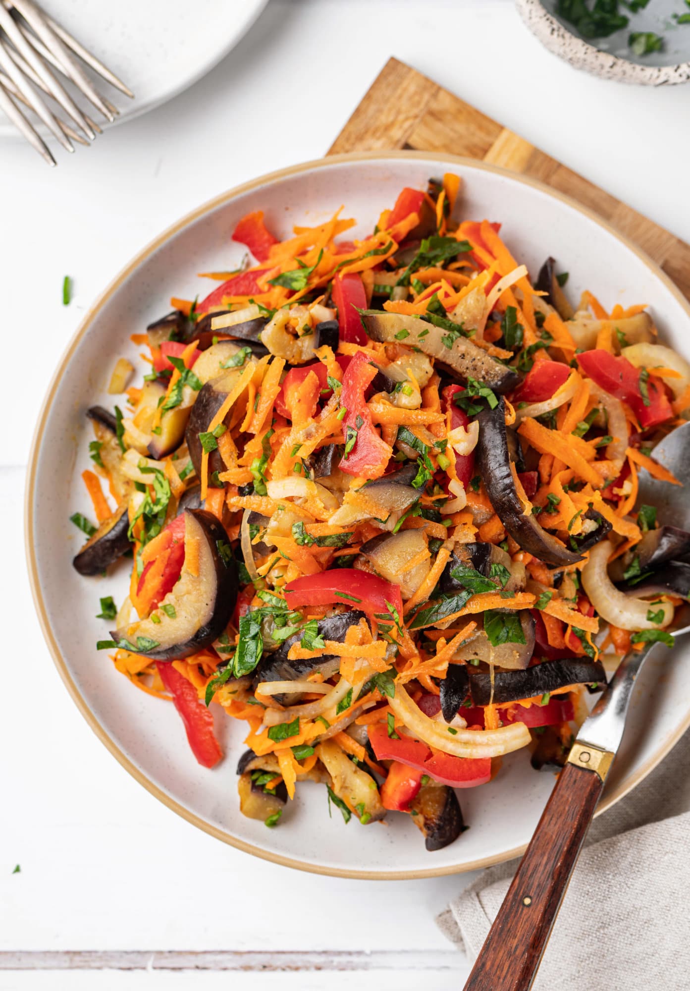 eggplant-salad-on-white-plate-on-a-cutting-board-with-spoon