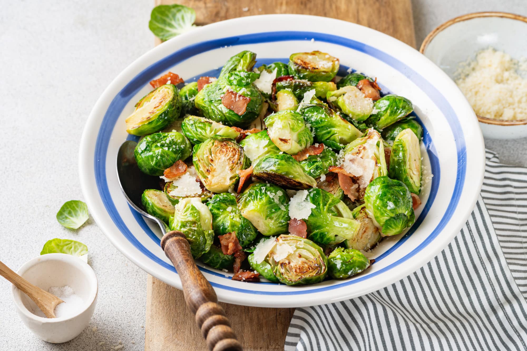 prepared brussels sprouts and bacon in a bowl with a spoon in the bowl.