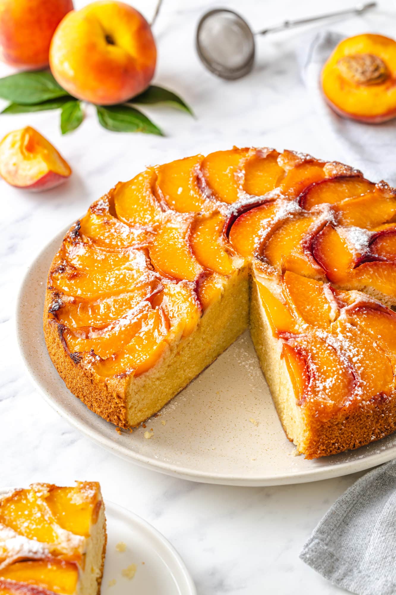 Peach upside down cake with a slice missing on a white plate.