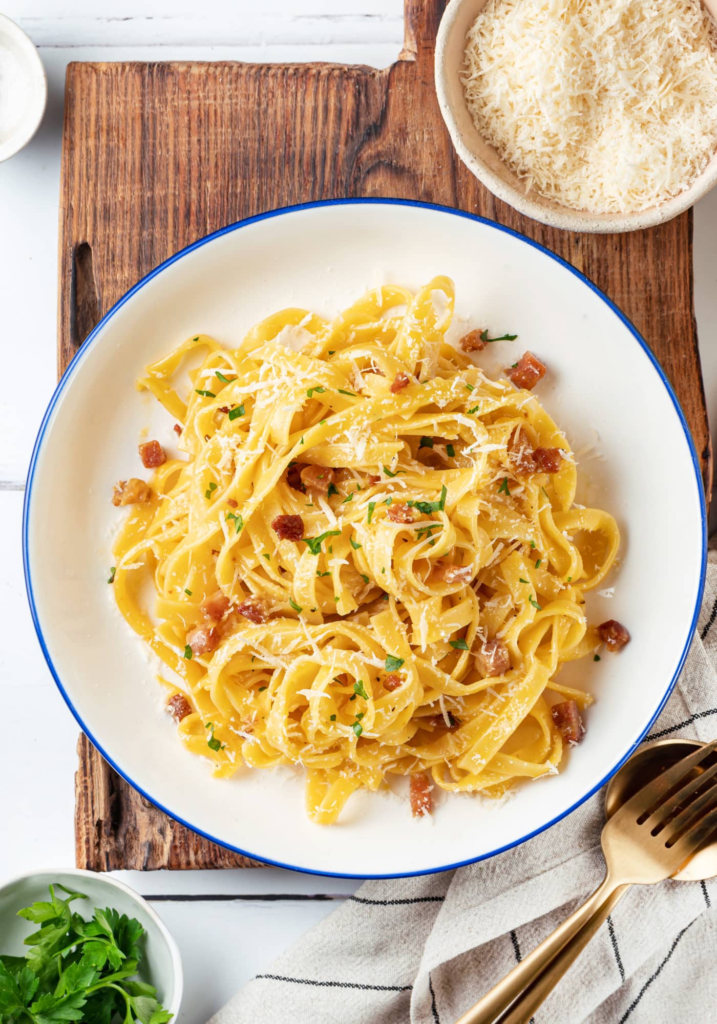 Pasta carbonara on a white plate on a wooden board.