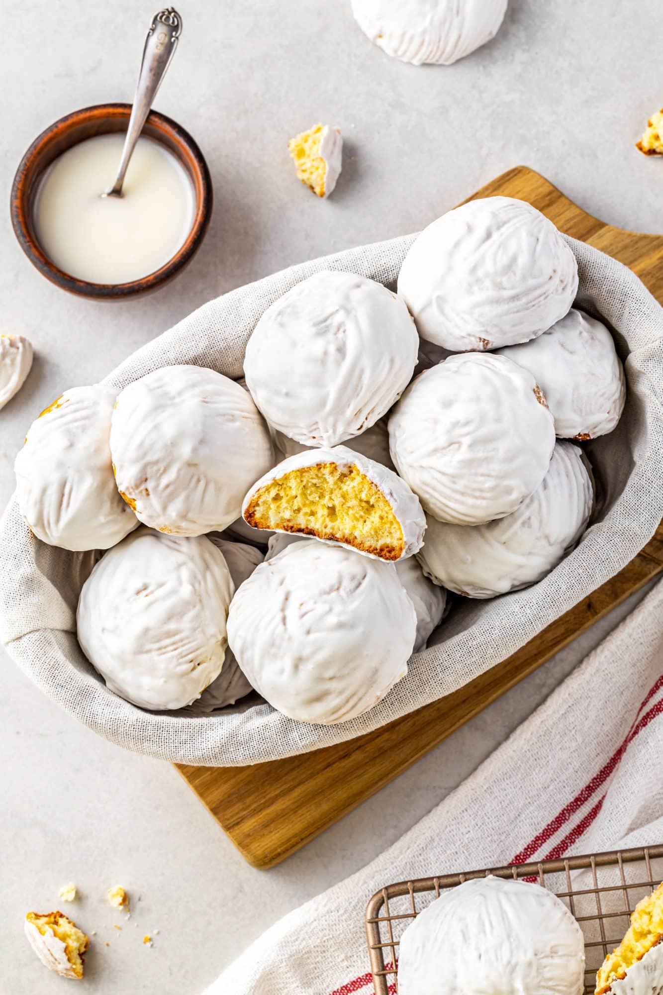 a bowl on a wooden board filled with glazed vanilla cookies.