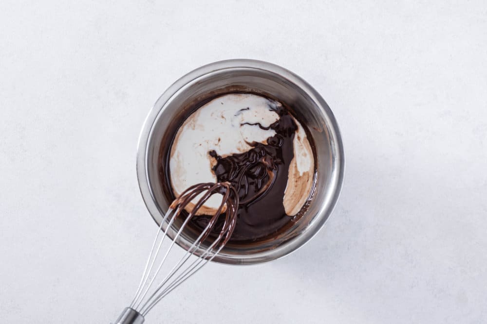 chocolate-glaze-being-mixed-in-a-silver-bowl-with-a-whisk