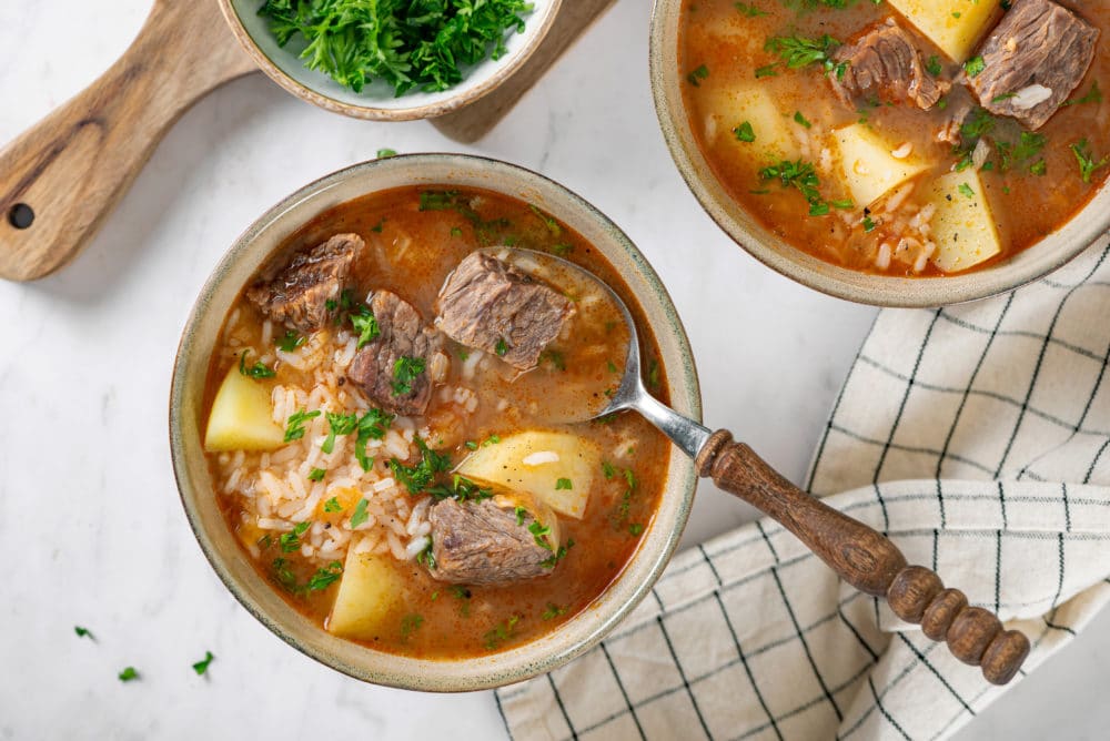 beef kharcho soup in a beige bowl with a spoon.