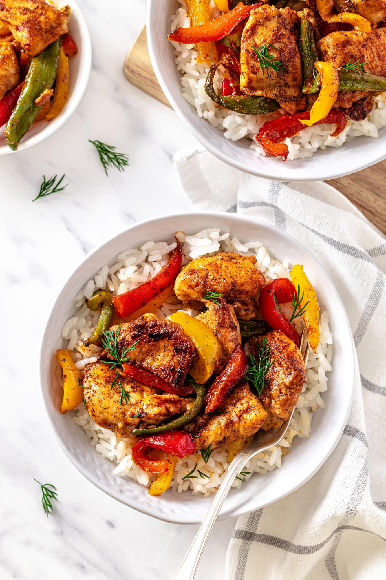 chicken-and-bell-peppers-with-rice-in-a-white-bowl-on-a-white-towel-with-a-fork