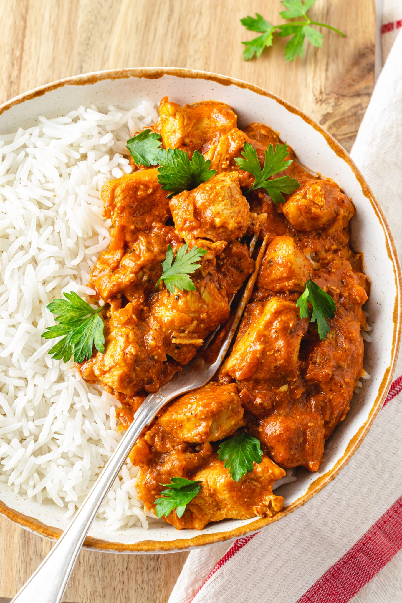 Indian butter chicken and rice in a bowl with a fork.