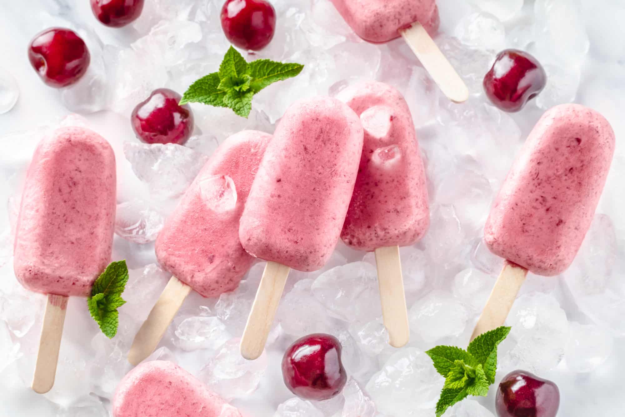 Cherry ice pops with cherries, ice, and mint around.