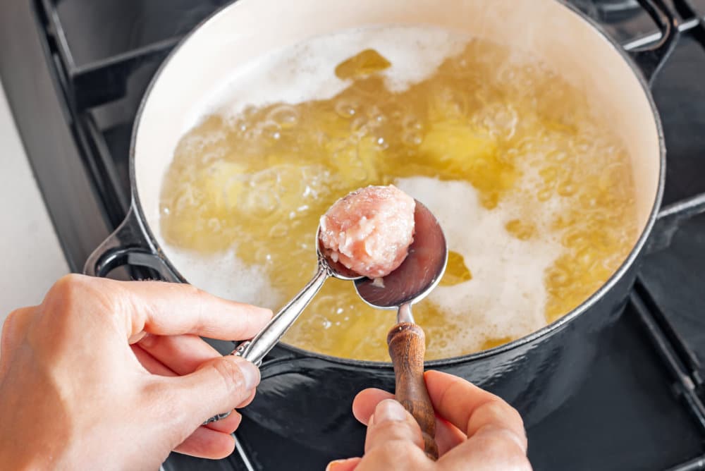 meatball-in-two-spoons-with-a-soup-pot-in-the-background