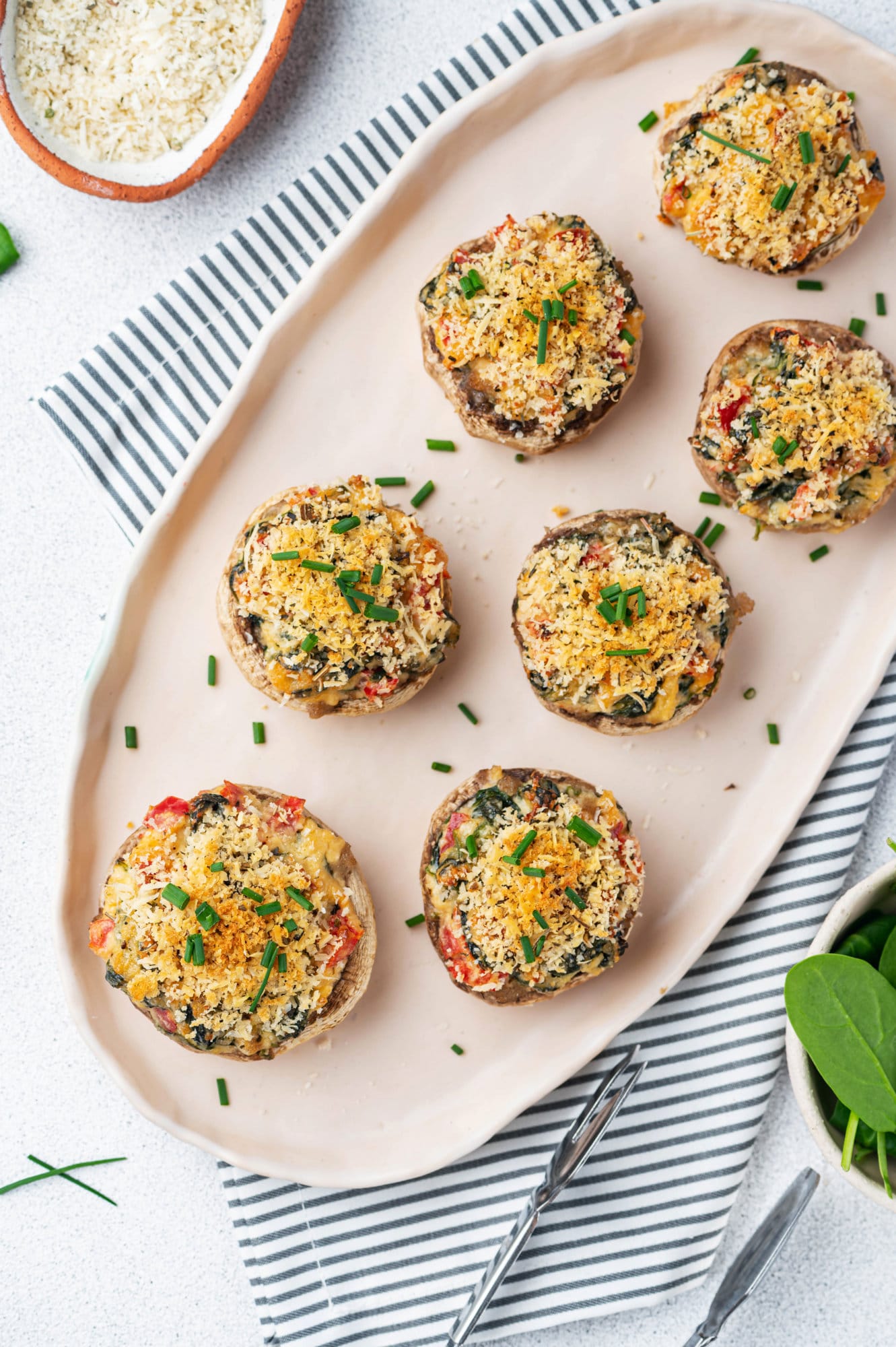 stuffed-mushroom-bites-on-beige-plate-with-striped-towel-and-tongs