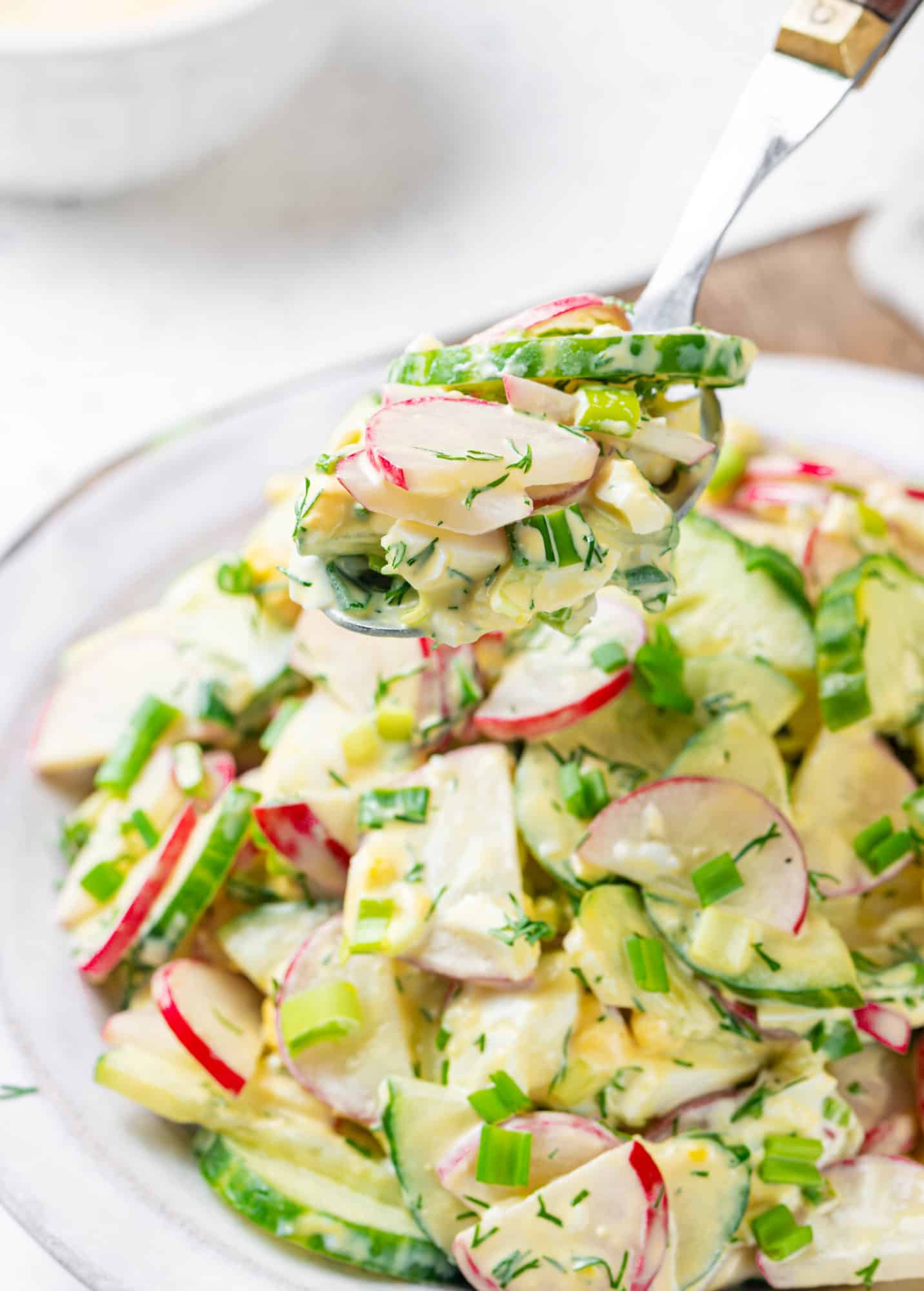 Radish cucumber salad in a bowl and close up on a spoon.