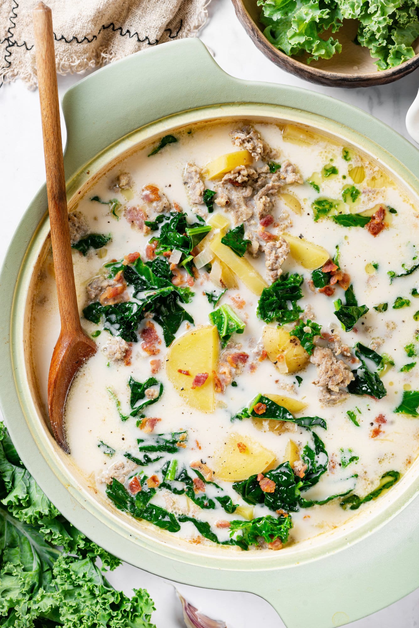 zuppa-toscana-in-a-green-soup-pot-with-a-wooden-spoon-and-kale-on-the-side