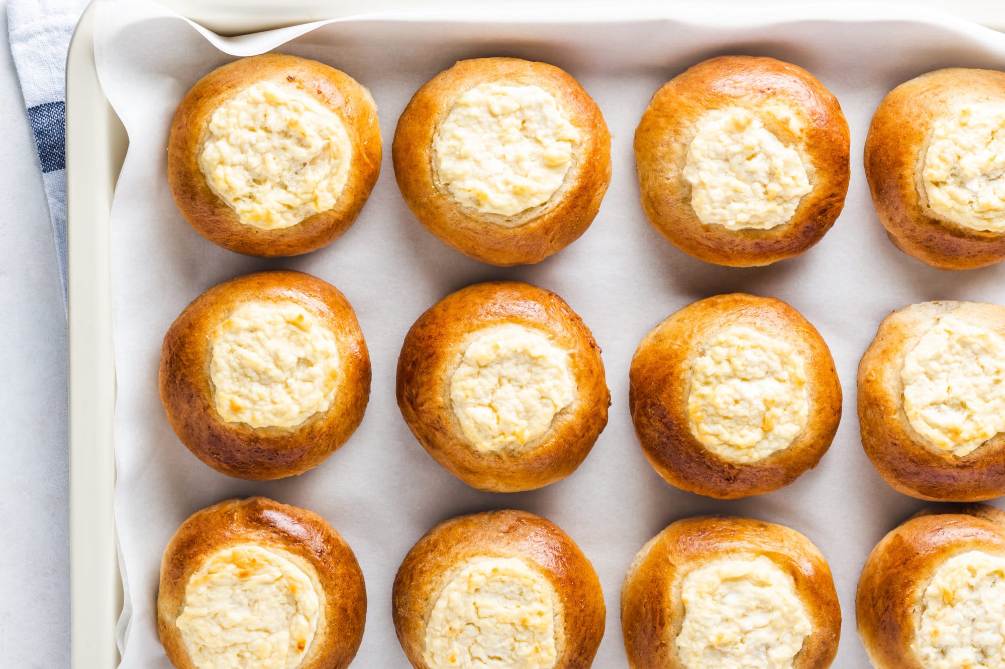 Russian sweet vatrushka buns on parchment paper on a baking sheet.