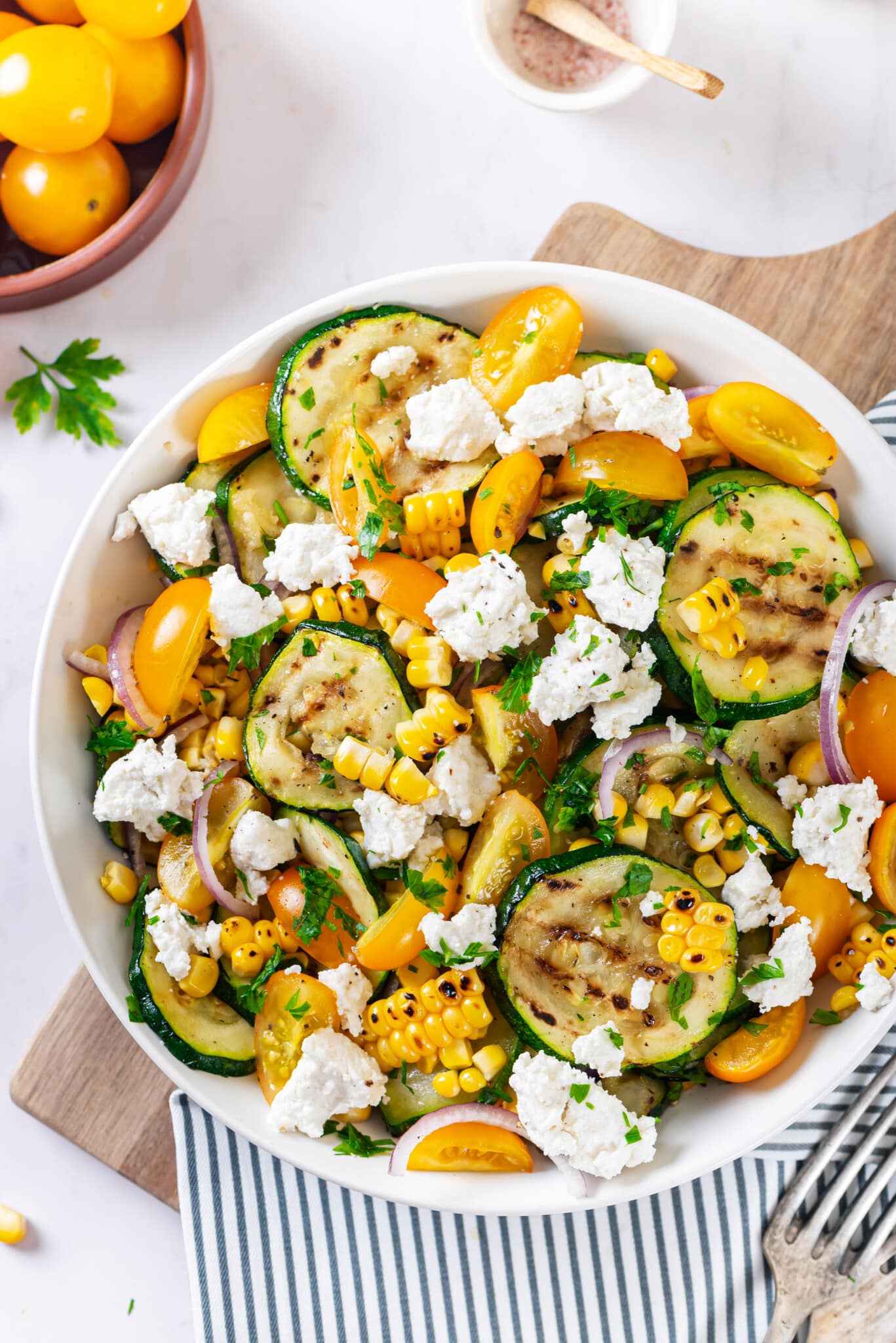 a large salad bowl filled with zucchini corn and cheese mixed together.