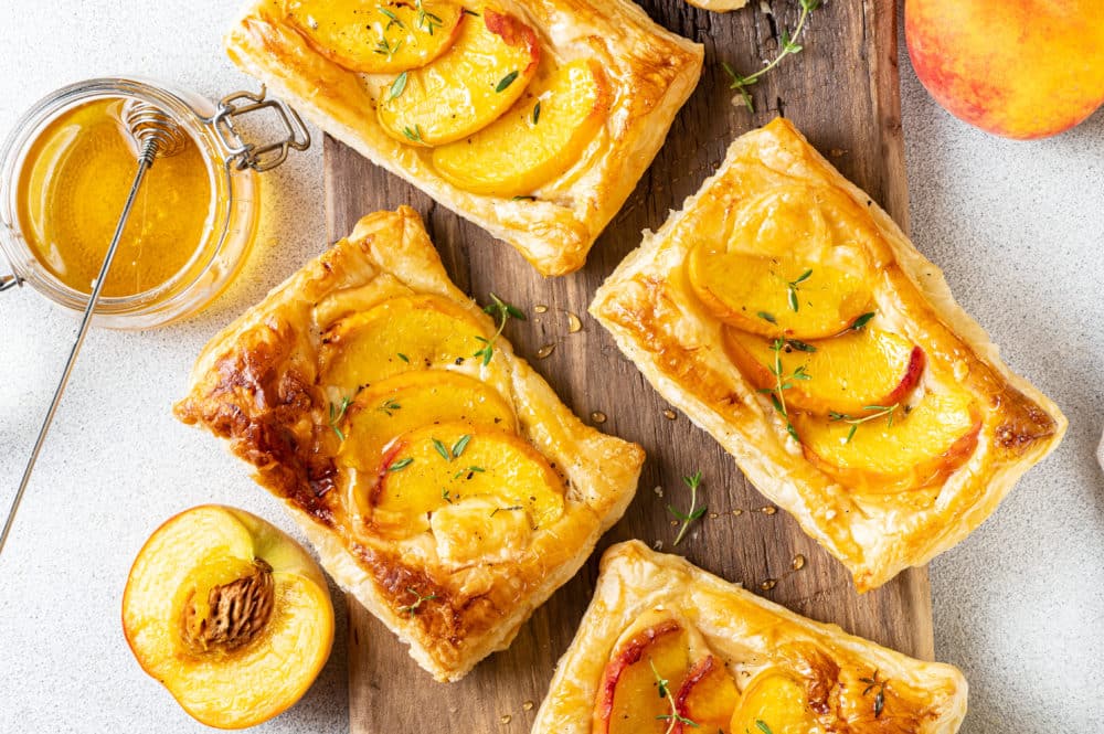 baked peach and brie tarts on a wooden board.