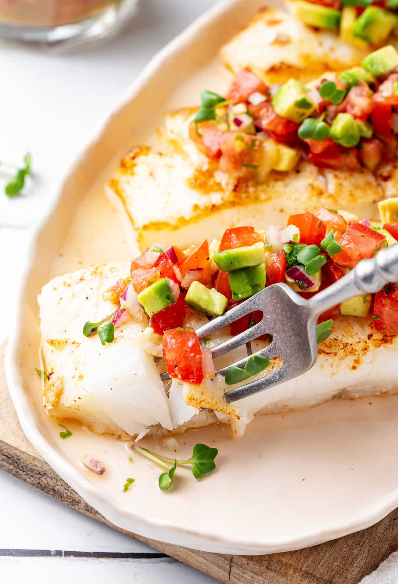 halibut-with-salsa-on-a-white-plate-on-a-wooden-board-with-a-fork