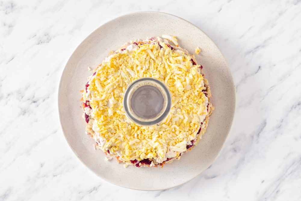 an egg layer to a layered salad on a white plate.