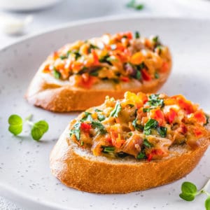 Bruschetta on a white plate with microgreens.