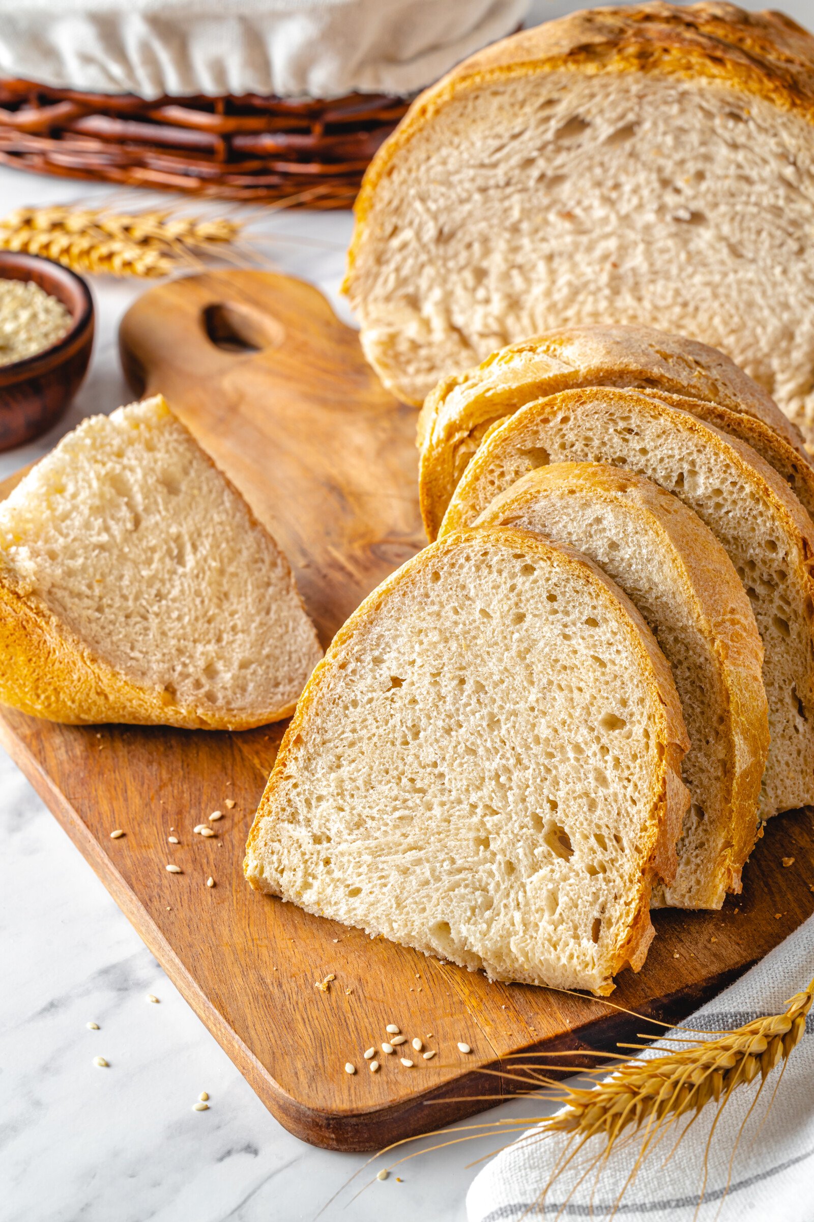 Baked bread slices on a wooden board with a wheat stalk on the side.