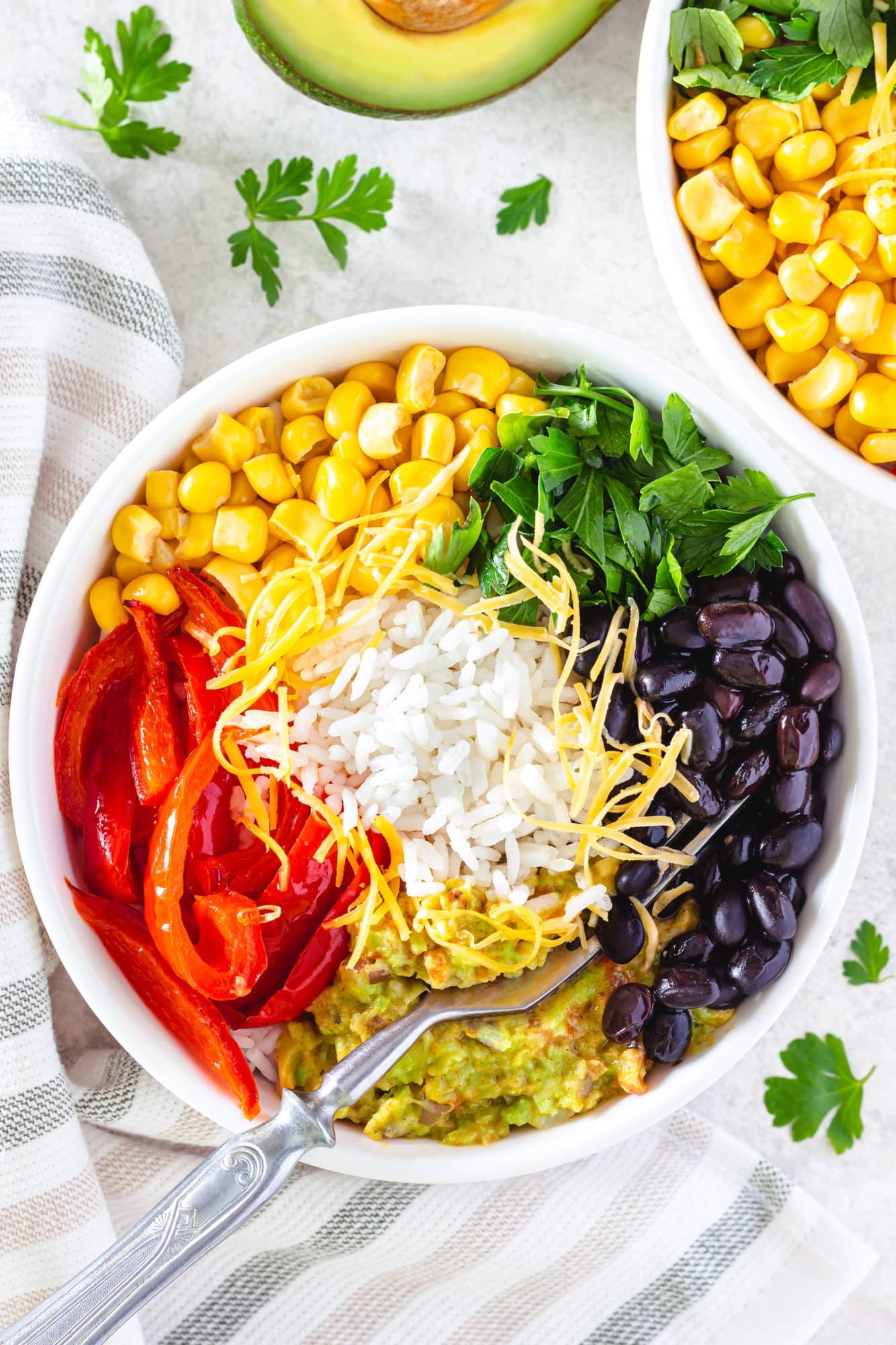 Veggie rice bowl on a towel with a fork and with parsley.