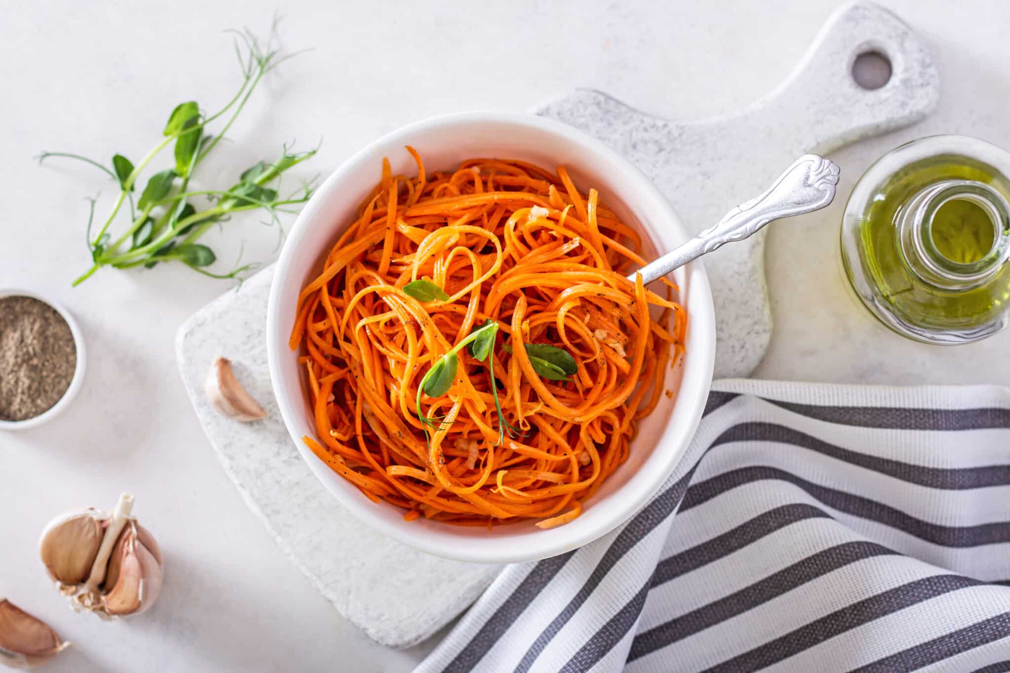 korean-carrot-salad-in-a-white-bowl-on-a-grey-board-with-a-fork