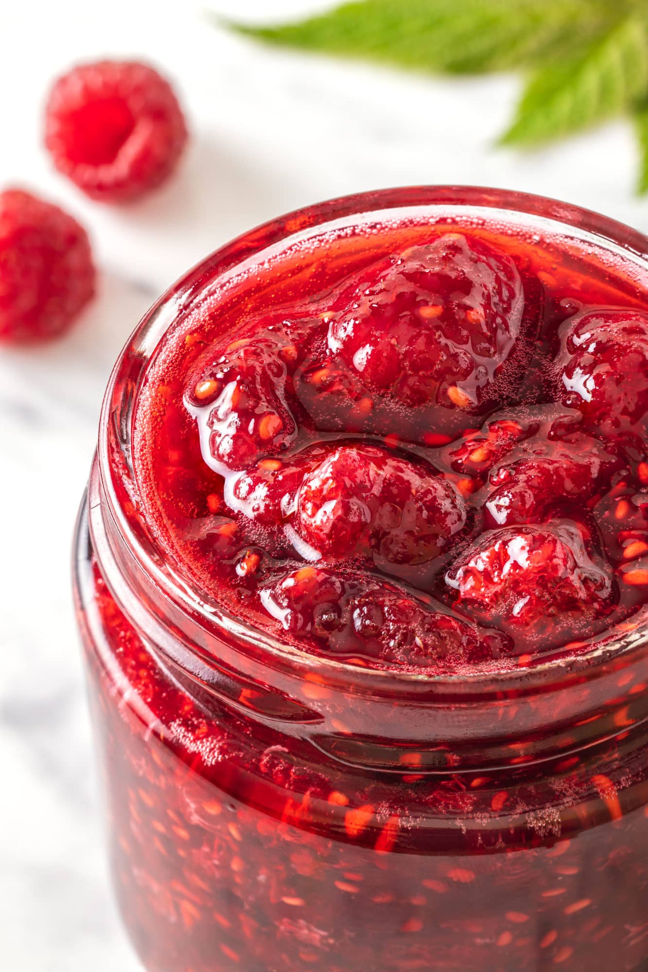 raspberry-jam-in-a-glass-jar-with-raspberries-in-the-background