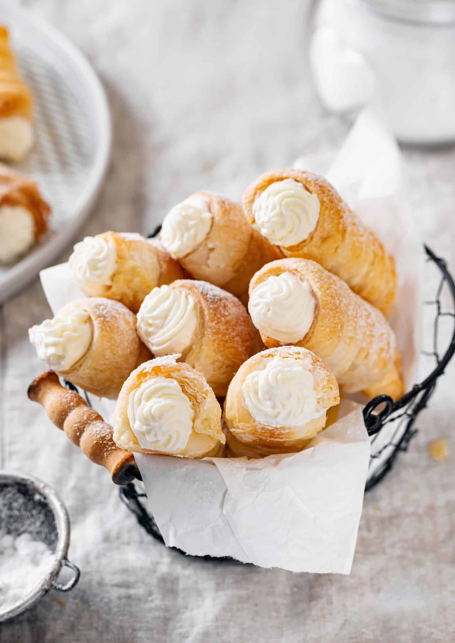 Cream horns in a black basket with parchment paper.