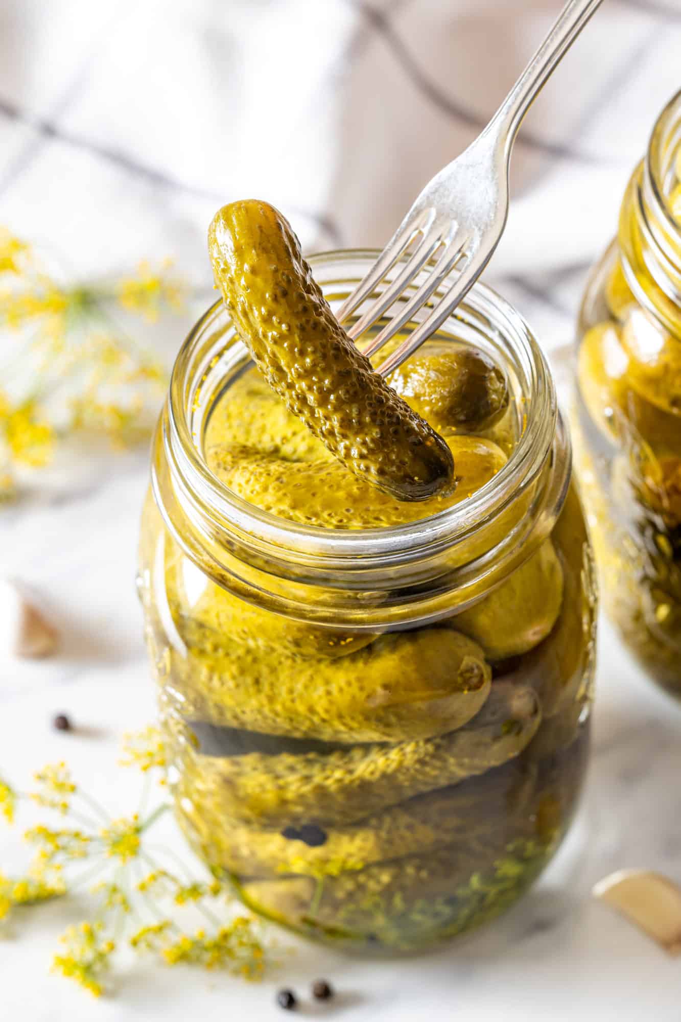 a jar of pickles with a fork spearing one pickle.