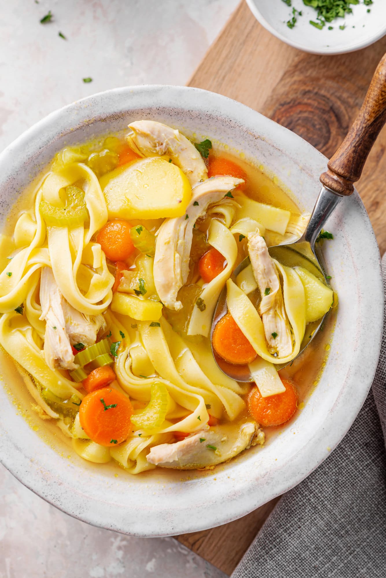 chicken-soup-in-a-white-bowl-on-a-wooden-board-with-a-spoon