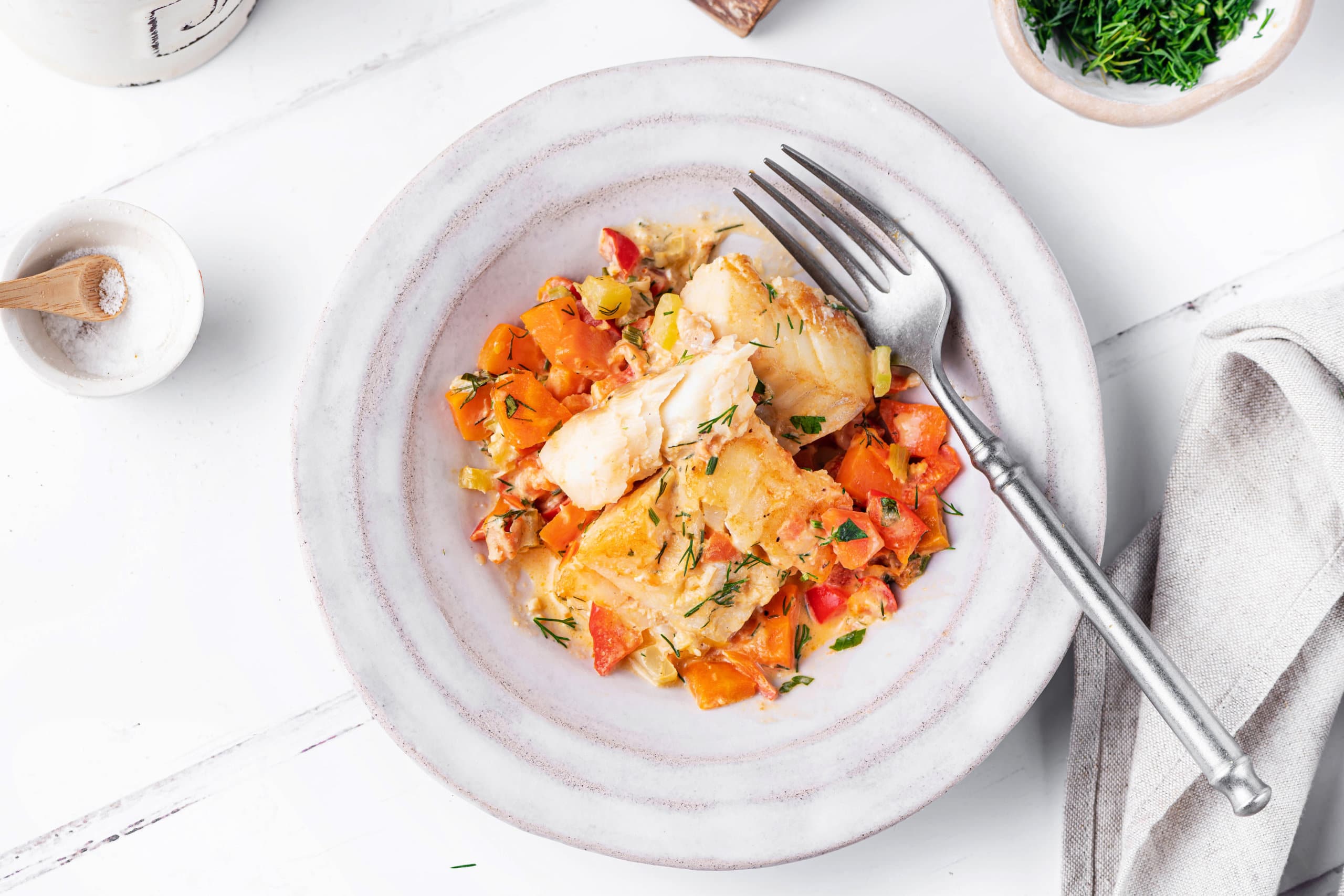 Fish and veggies in a bowl with a fork.