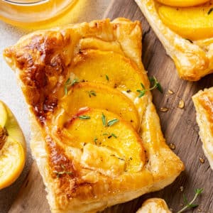 baked peach brie tart on a cutting board.