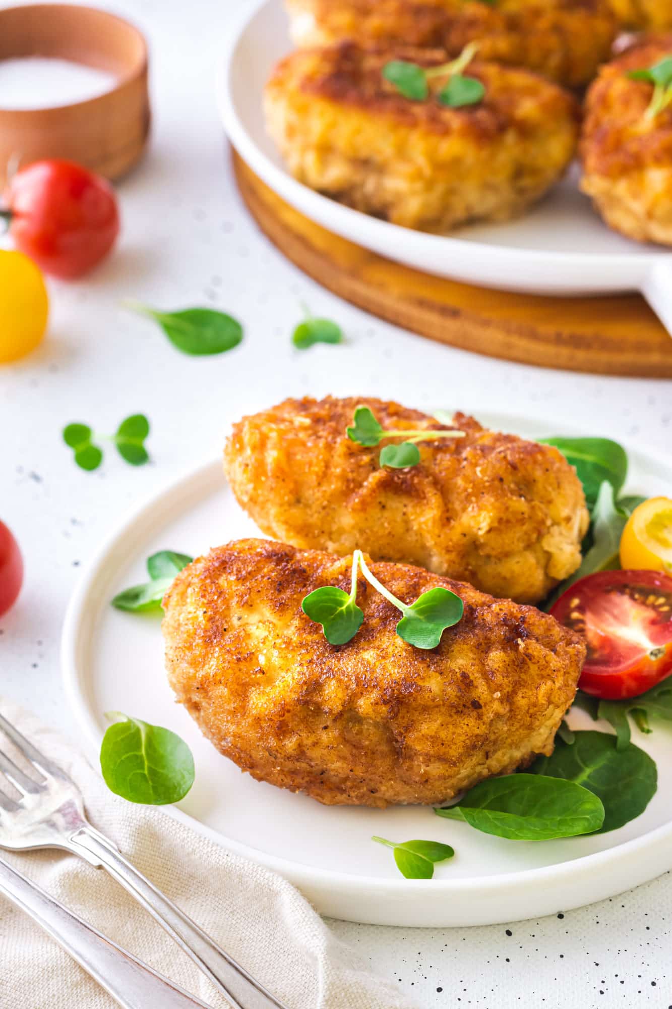 a white plate with prepared stuffed chicken and microgreens.