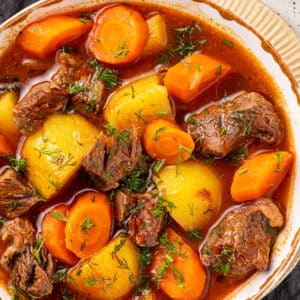 stew in a bowl on a plate on a dark grey towel.