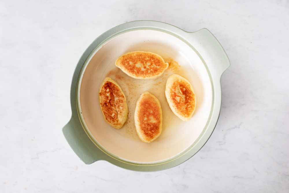 Piroshki frying in a pot.