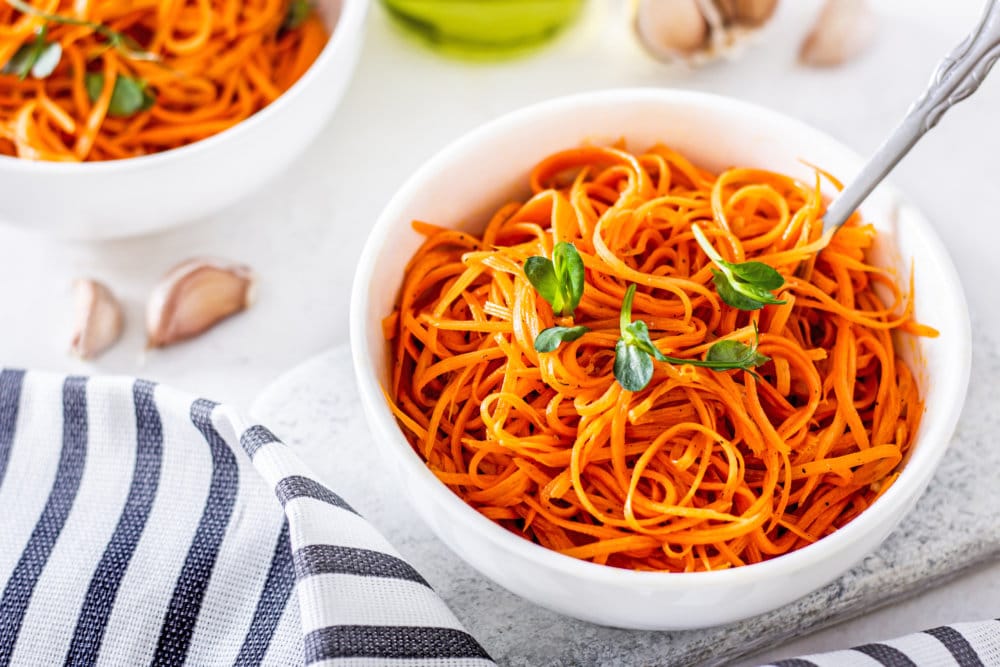 korean-carrot-salad-in-a-white-bowl-on-a-grey-board-with-a-fork