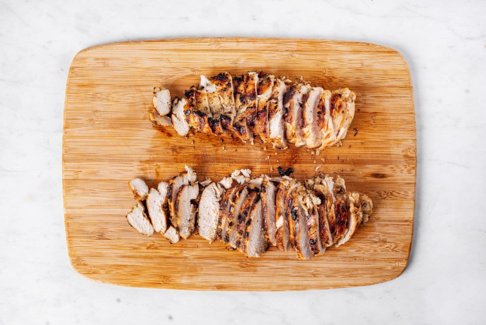 sliced marinated grilled chicken on a cutting board.